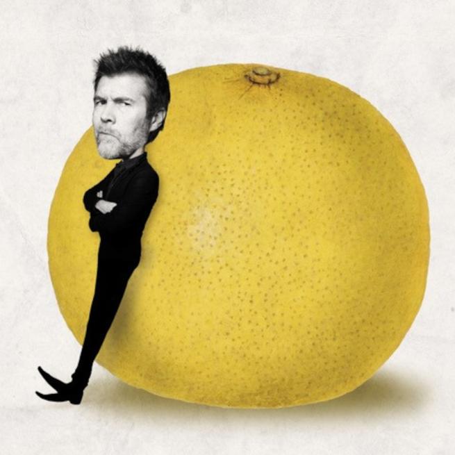 Rhod Gilbert stands in front of a giant grapefruit. 