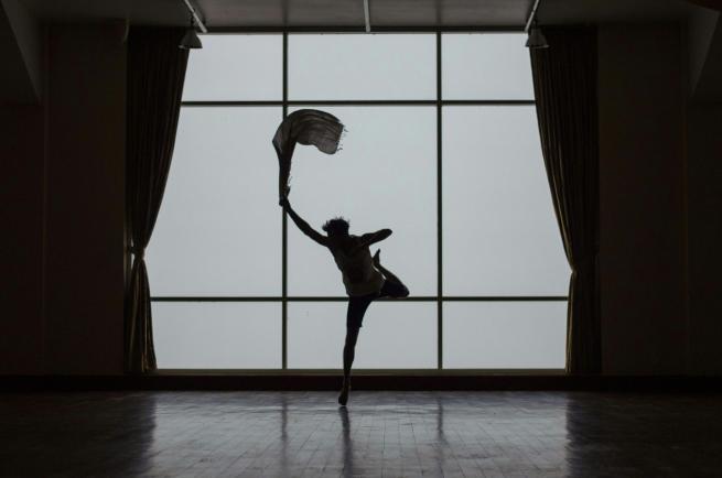 A silhouette of someone dancing in front of a window