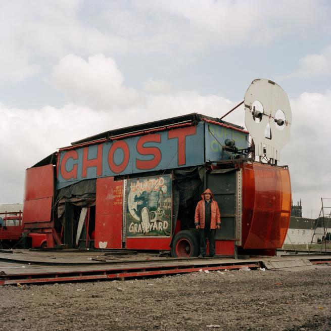 An atmospheric photograph of a man in a red hooded jacket stood in front of a disused ghost train