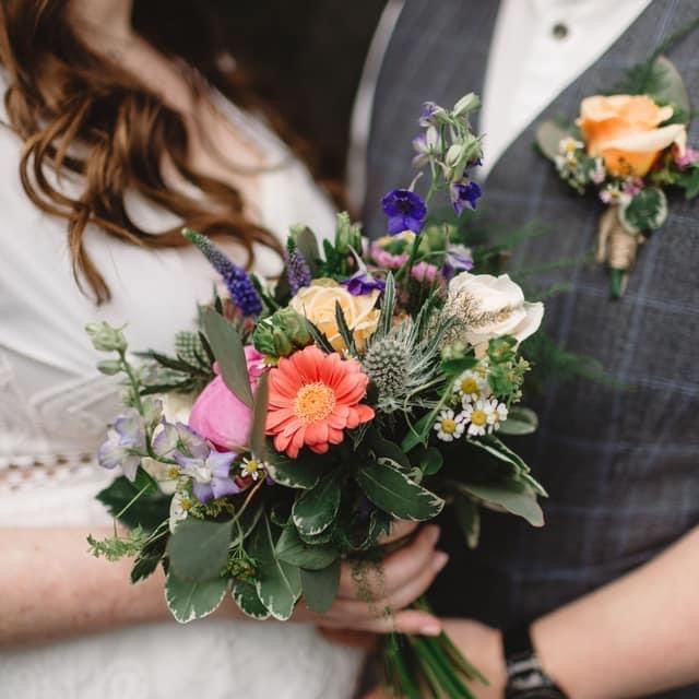 a bride holding a bouquet of flowers and a groom with a matching buttonhole