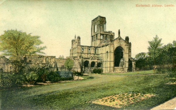 a tinted colour postcard view of Kirkstall Abbey, with gardens to the foreground