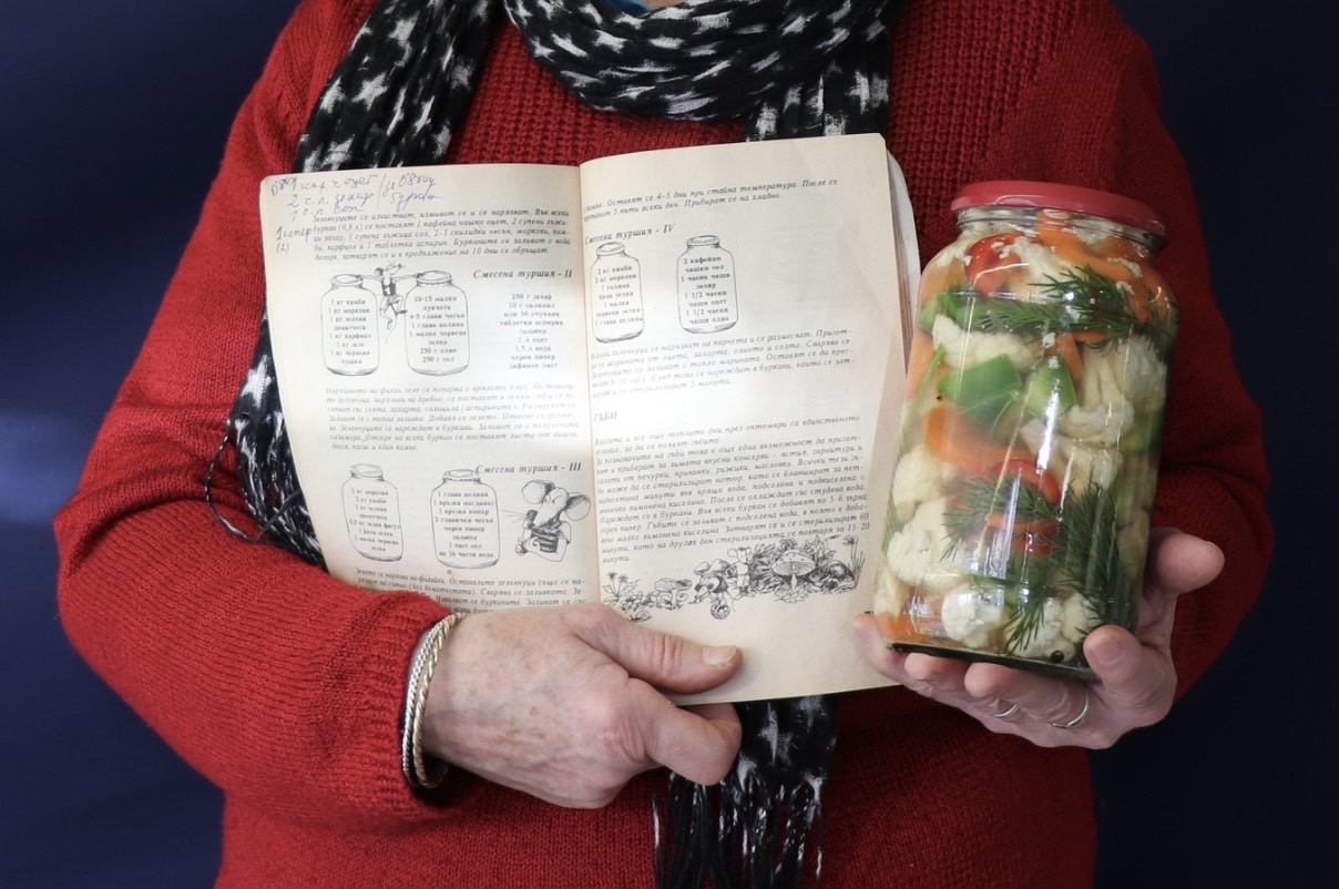 Woman holding a jar of pickles and a recipe book