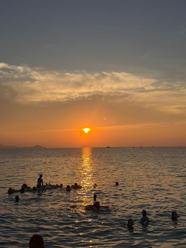 Bathers watch the sun set over Koh Samui from the sea 