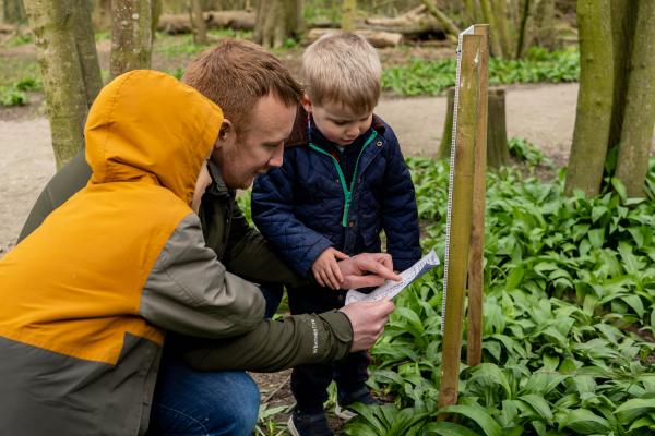 Two children and parents looking at a sheet of paper whilst outside.
