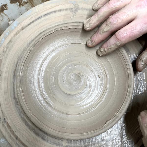 A hand throwing a ceramic plate