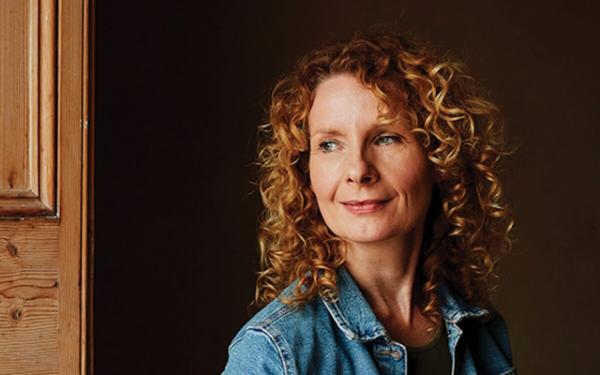 A woman with curly hair and a denim jacket.