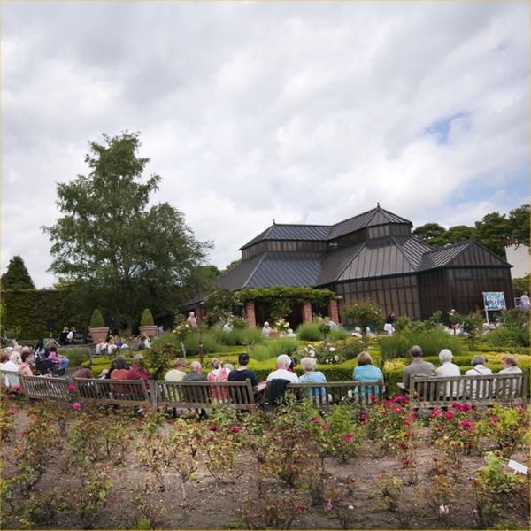 People sat outside watching a band perform in a park. 