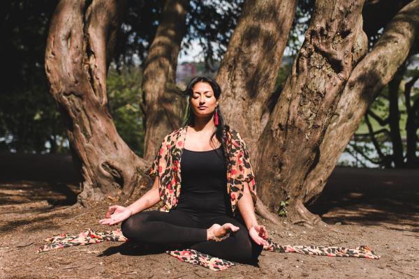 Picture of a person sitting in front of a tree with their eyes closed