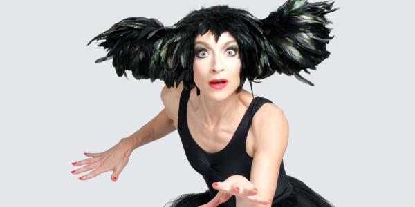 A person wearing a black dress and black feathers on their head.
