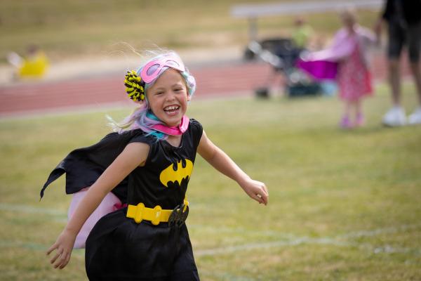 Young girl dressed as superhero, taking part in fun run 