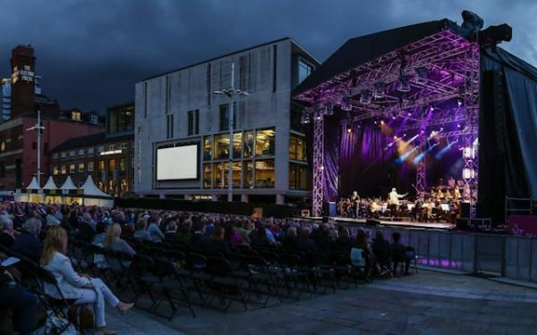 An outdoor stage with people watching.