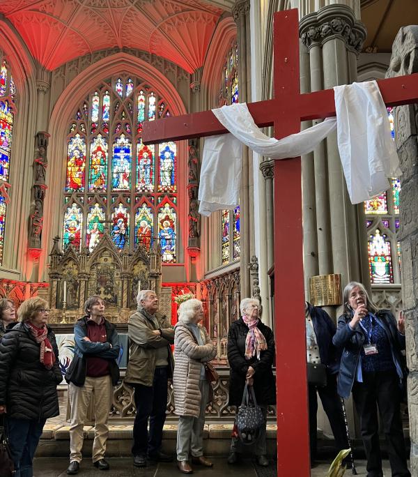 A Leeds Minster tour guide points out the Leeds Cross