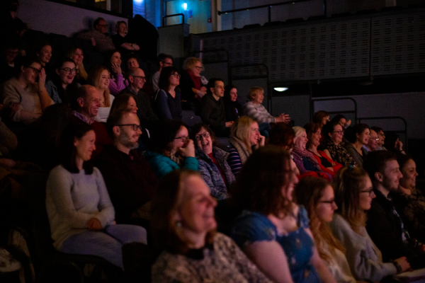 Audience members in a darkened theatre space