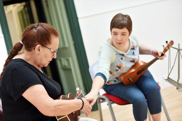 Image showing ukulele lesson with a tutor pointing out how to play ukulele to student