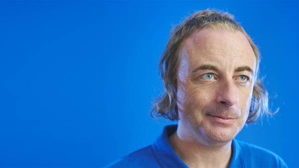 Paul Foot in front of a blue background