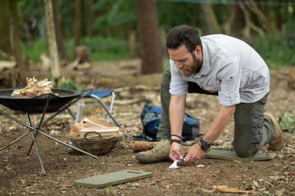 Person bending down to place items in a woodland setting