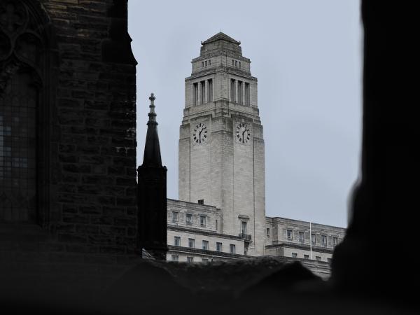 Leeds University Parkinson Building behind dark, Gothic-looking church stonework.