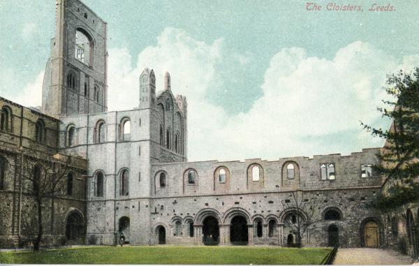 A picture of a monastic ruin. A grassed cloister area is to the foreground and a church bell tower is to the right.