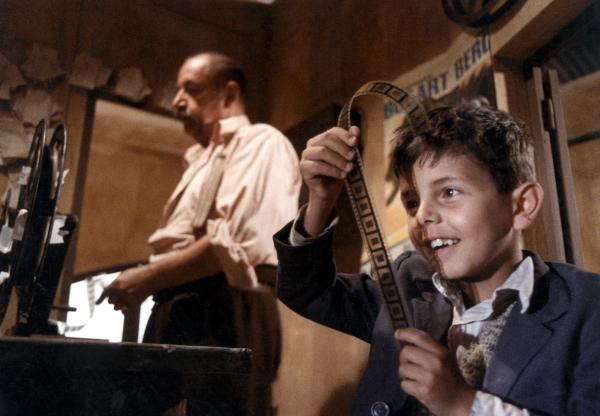 An iconic still from Cinema Paradiso featuring Totò (played by Salvatore Cascio) inspecting film reel.