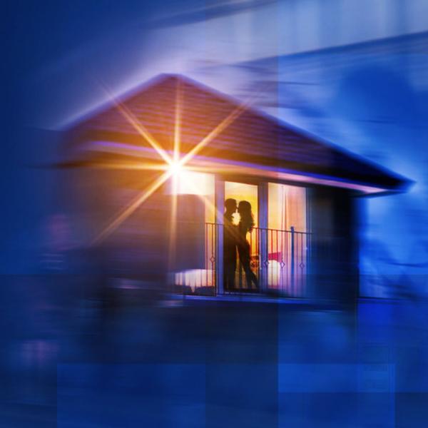 Silhouette of a couple in an embrace seen through a window. Outline of a cabin also appears. Everything is blurry.