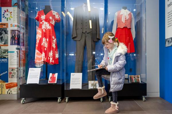 A colour photo of a child doing a trail in front of museum displays.