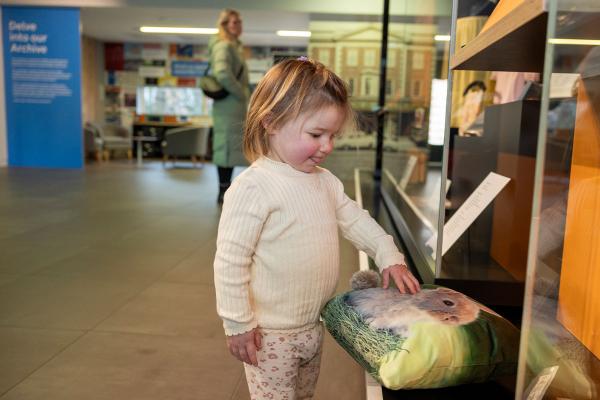 A colour photo of a child touching a cushion in a museum display.