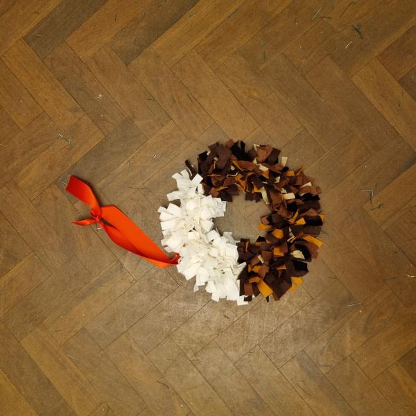 A photograph of a rag rug wreath in the colours of a Christmas pudding.