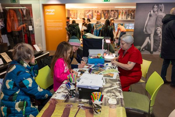 A colour photo of a family doing a craft activity in a colourful museum space.