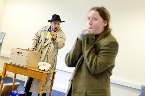 A woman looks nervous as a detective in a wide brimmed hat questions her