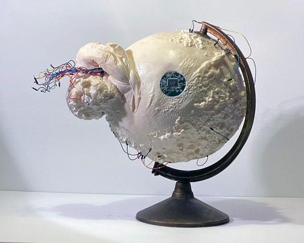 A sculpture depicting a globe with electronics bursting forth