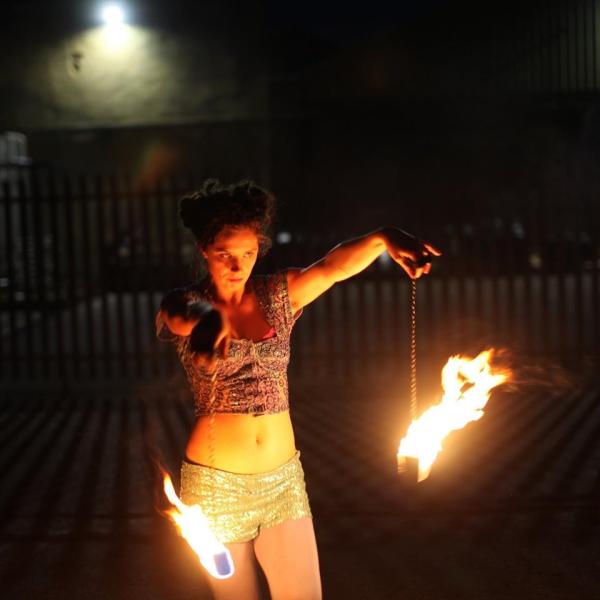 One of our fire circus performers holding lit fire poi as part of their routine