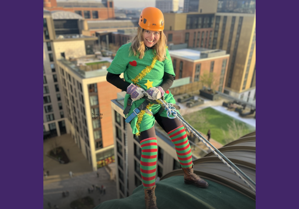 A lady dressed as an elf abseiling down a building