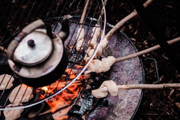 A kettle and bread cooking over a campfire