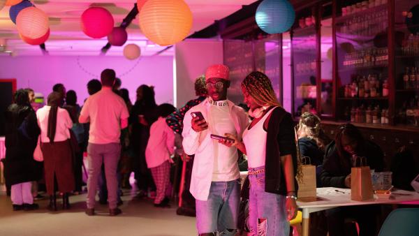 Two young people stood in the foreground of a busy party atmosphere.