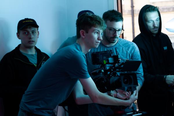 A group of four men, with one holding a camera.