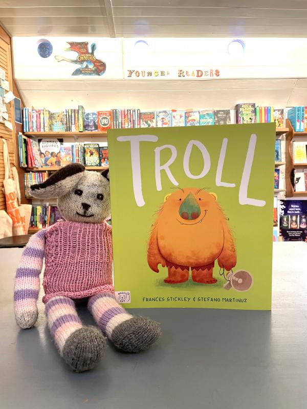 A white rabbit soft toy holds a copy of a book called Troll