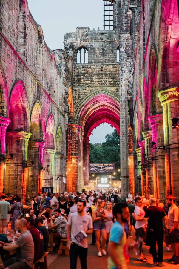 Kirkstall Abbey Church lit up at night with people drinking beer