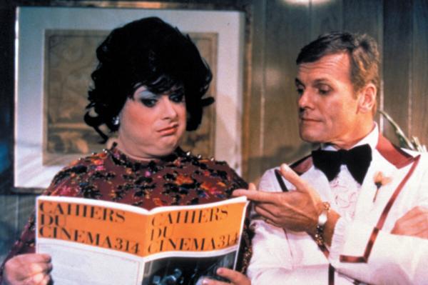 A screen cap from the film Polyester showing characters Francine and Elmer Fishpaw played by Divine and David Sampson looking at a magazine