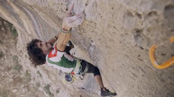 Andrew Bisharat climbing in Palestinian flag colours red, white and green