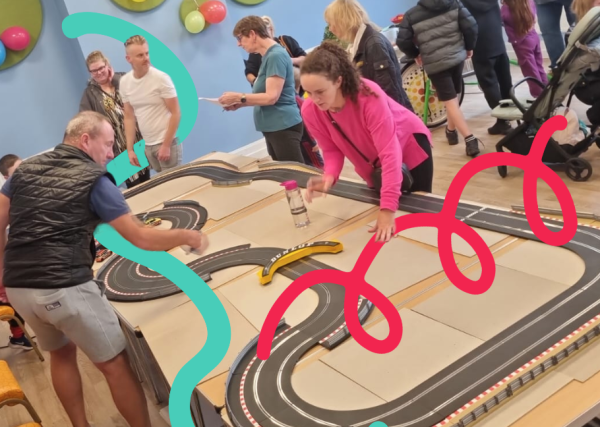 A large electric racing car game being played by a man and women