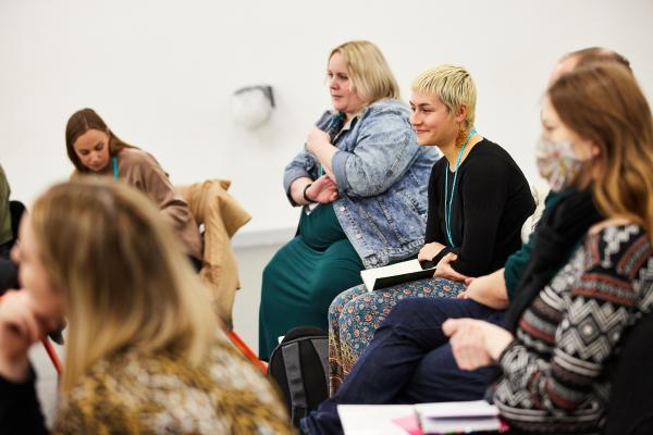 Artists sit listening to a speaker