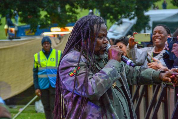 Image of Luciano an international reggae artist singing into a microphone reaching out his hand towards a crowd at the black music festival 2024