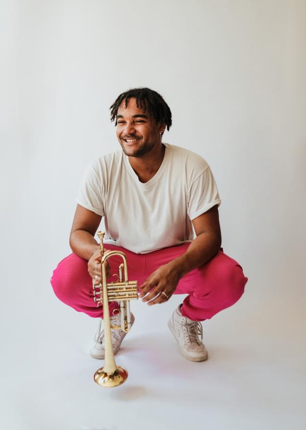 A musician bent down holding a trumpet. 