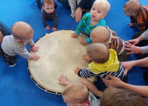 Image of babies around a large drum on the floor