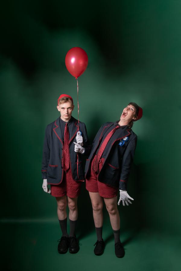 Girl and boy twins in black and red uniform hold a red balloon