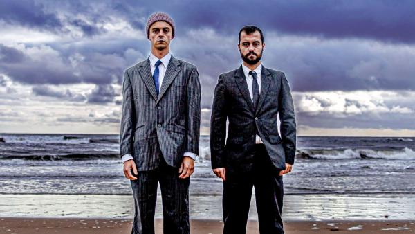 Two people in suits standing in front of the beach.