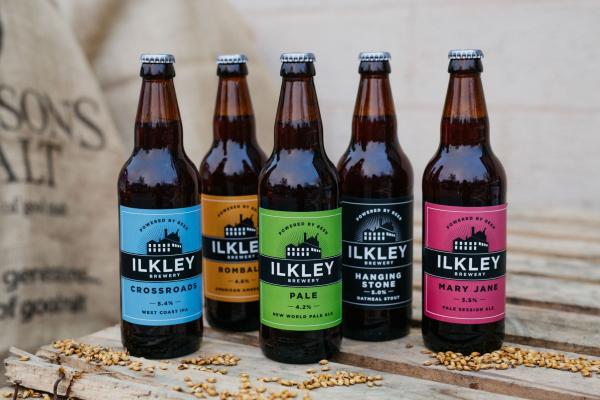 6 Ilkley Brewery beer bottles with different coloured labels lined up next to each other.