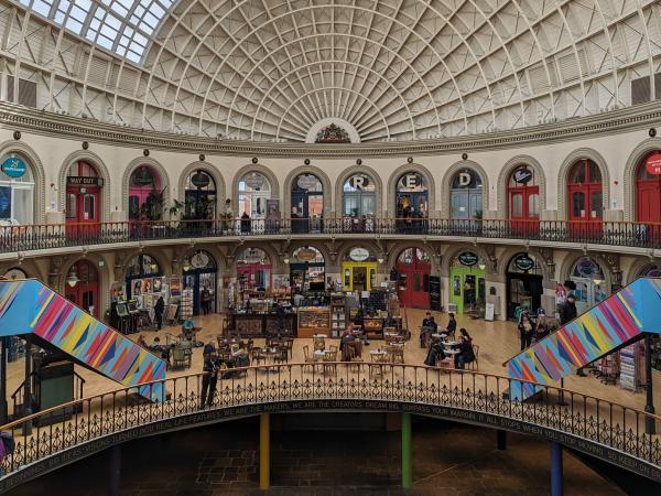 The interior of Leeds Corn Exchange from the upper balcony looking down, an oval shaped Victorian-era building, with independent shops