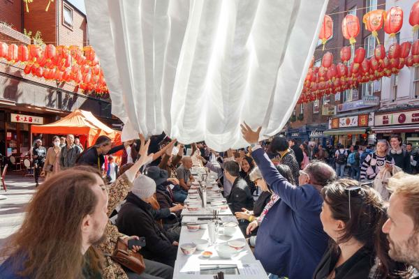 People sat around a table outside sharing a meal in Chinatown in London