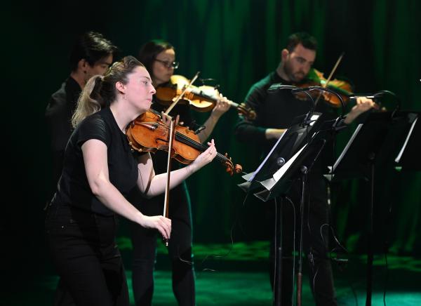 A musician sat playing a violin. 